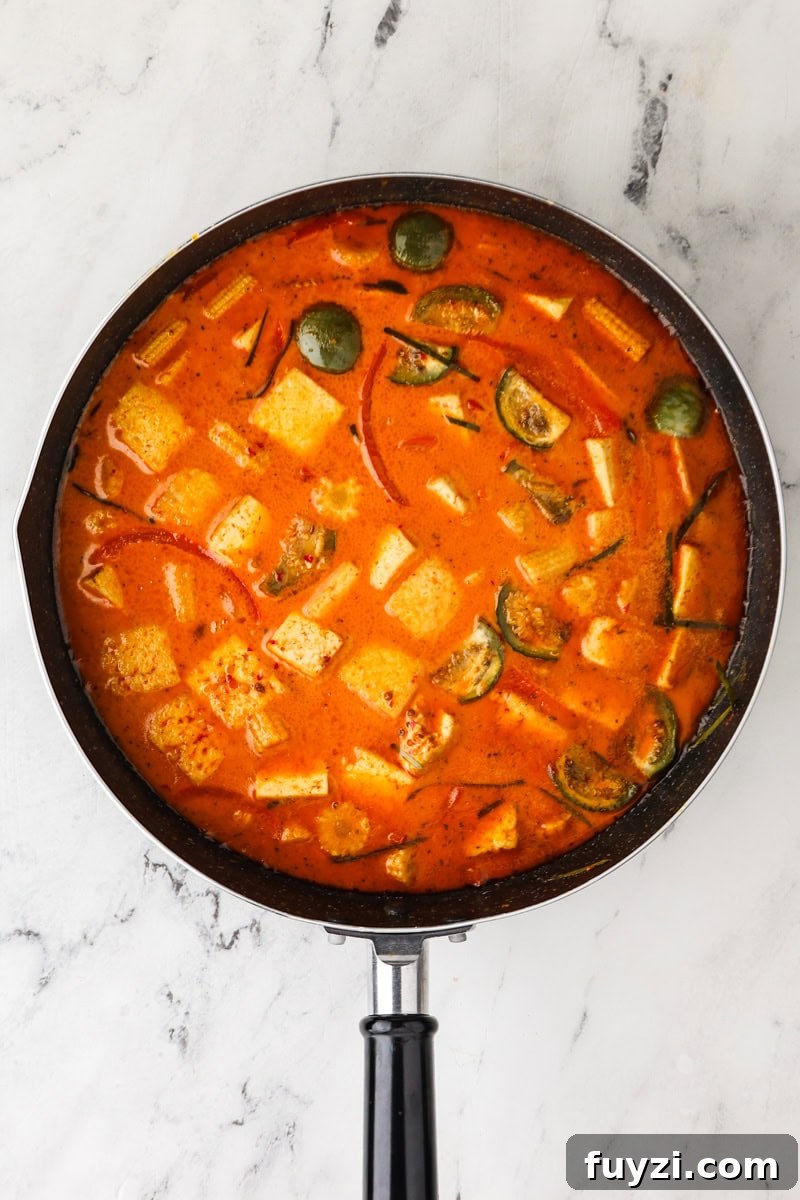 An overhead image of adding the tofu, makrut lime leaves, fish sauce, and coconut sugar.