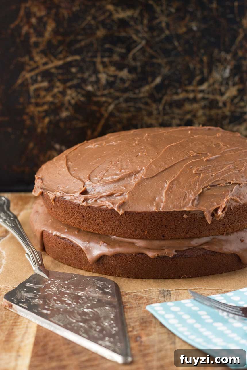 A whole chocolate orange cake on a wooden board with a decorative cake slice.