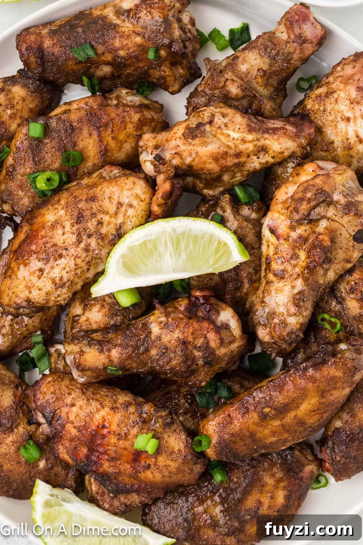 Jerk Chicken Wings topped with chopped green onions and fresh lime wedges