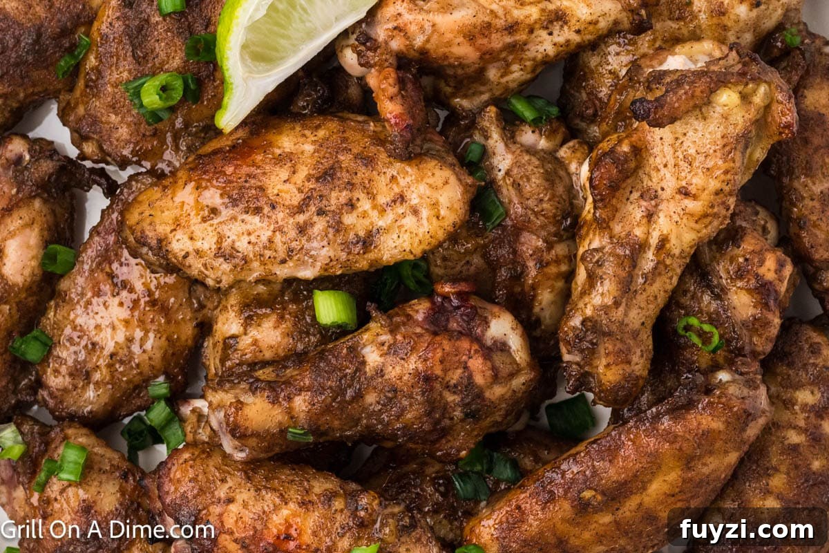Jerk Chicken Wings stacked and topped with green onions and fresh lime wedges