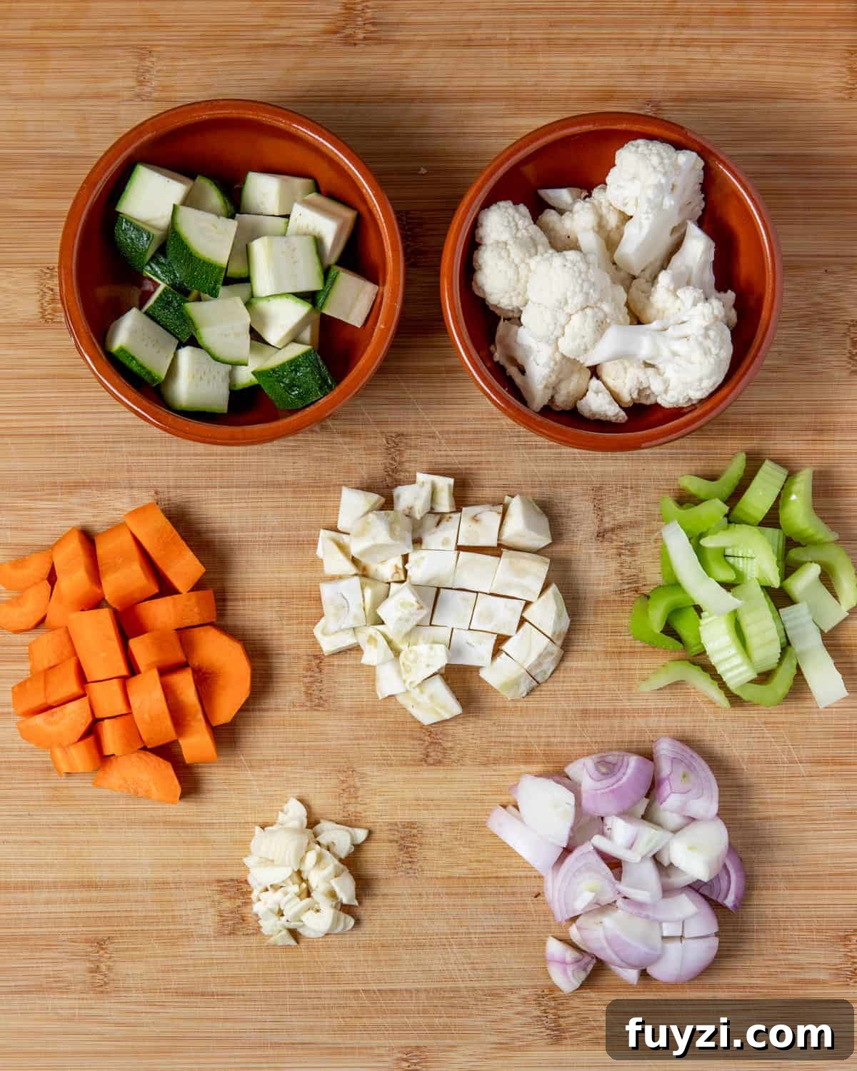Vegan Smoked Tofu and Vegetable Stew 5 Photo showing each of the vegetables cut into chunks in little piles on a wooden chopping board.