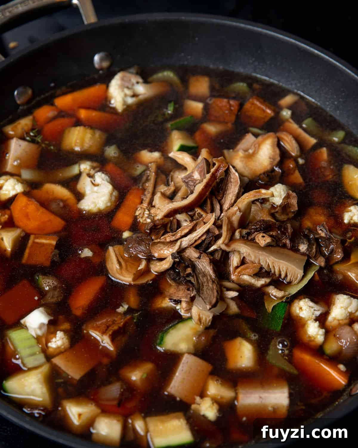 Vegan Smoked Tofu and Vegetable Stew 7 Photo of soaked mushrooms and mushroom soaking water being stirred in to the pan.