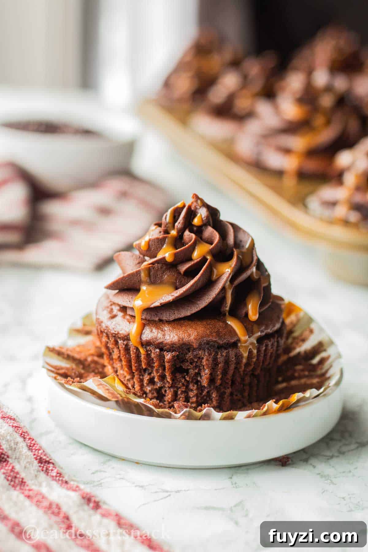 Gooey Chocolate Caramel-Filled Cupcakes Recipe 2 Unwrapped chocolate cupcake with frosting and caramel drizzle on top.