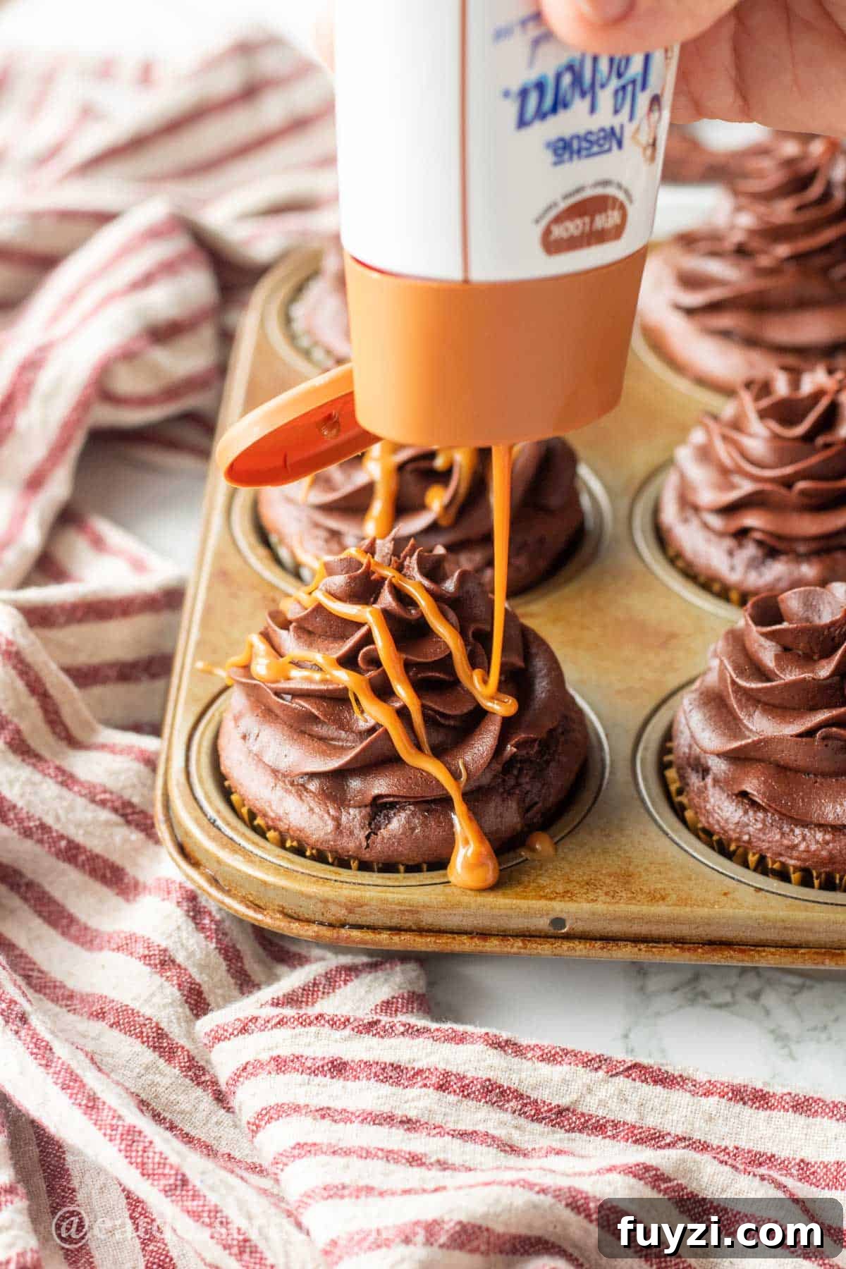 Gooey Chocolate Caramel-Filled Cupcakes Recipe 9 Pouring caramel drizzle over chocolate frosted cupcakes.