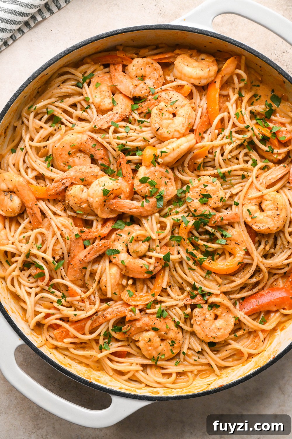 A large skillet of dairy free cajun shrimp pasta, garnished with fresh parsley.