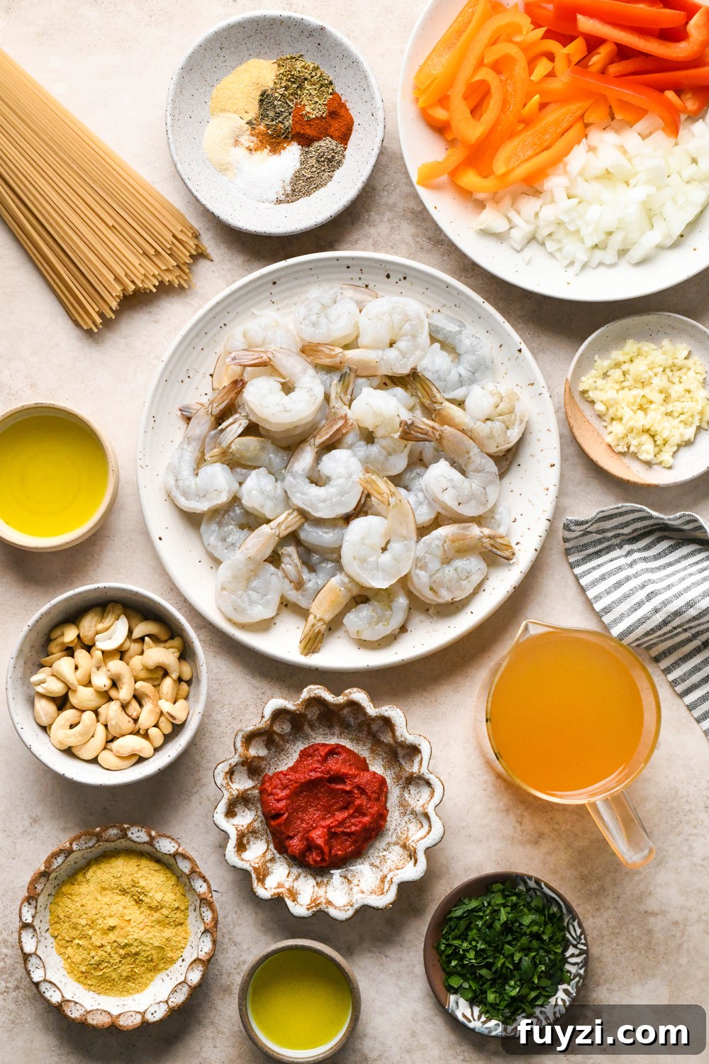 Ingredients for dairy free cajun shrimp pasta in various ceramics on a creamy brown background.