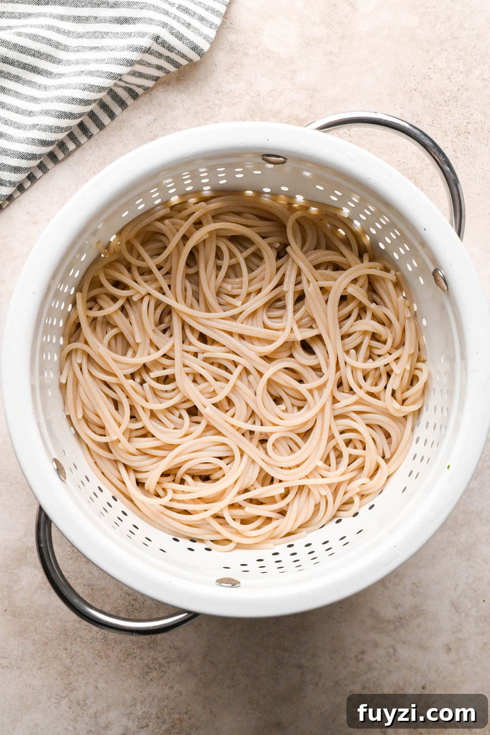 Cooked gluten free spaghetti in a white colander