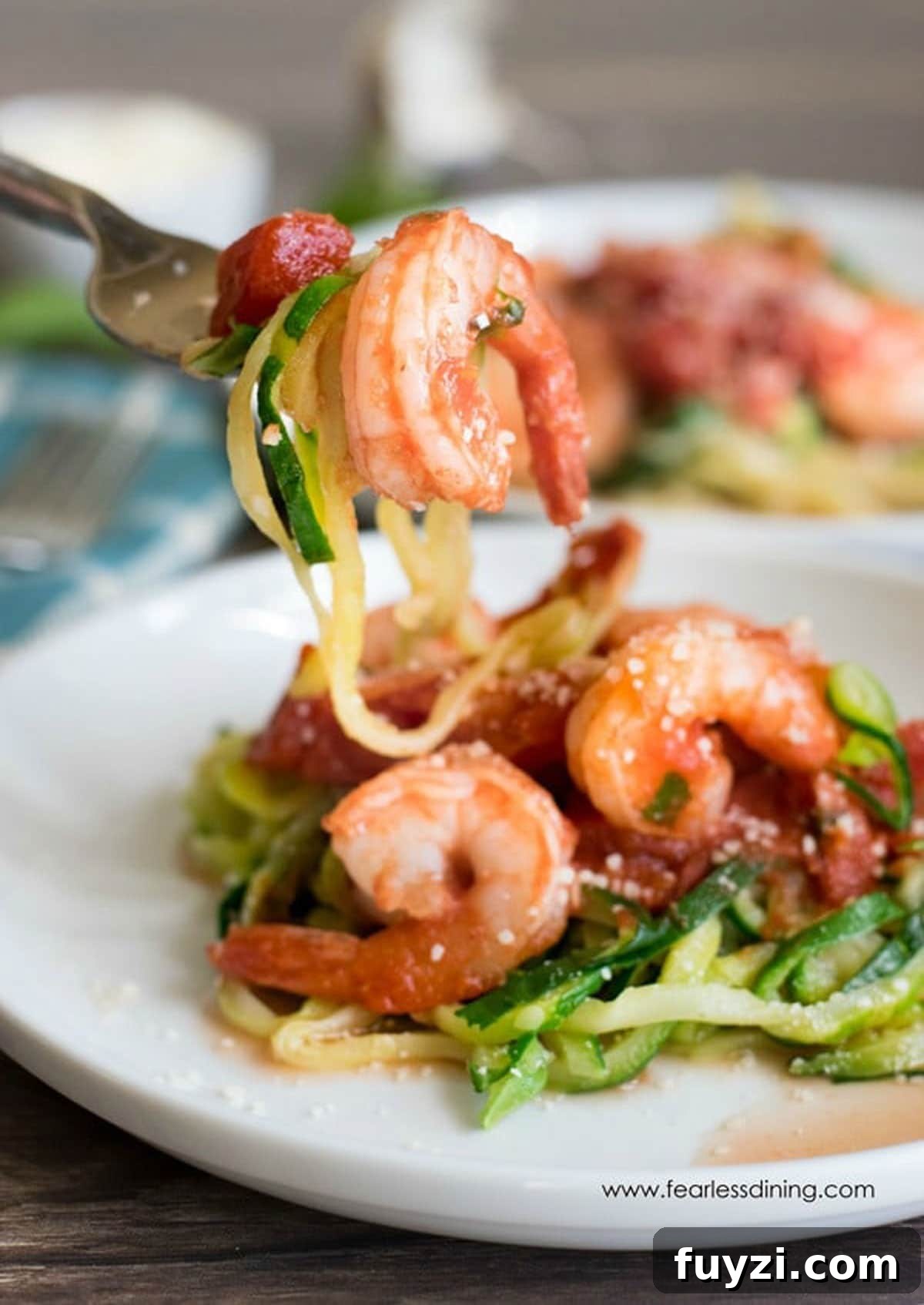 a fork full of zucchini noodles and a cooked shrimp