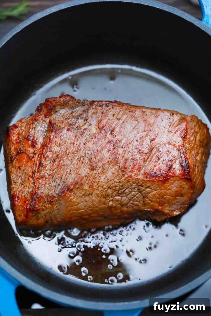 Slow-Cooked Guinness Pot Roast Recipe 5 searing a chunk of beef in a Dutch oven
