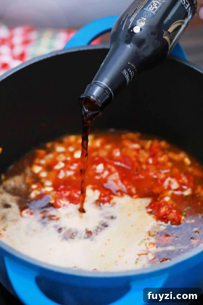 Slow-Cooked Guinness Pot Roast Recipe 7 adding Guinness beer to a Dutch oven with onion and tomato paste