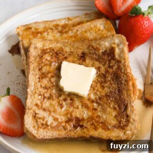 Three slices of high protein french toast on a white plate topped with a pat of butter and maple syrup