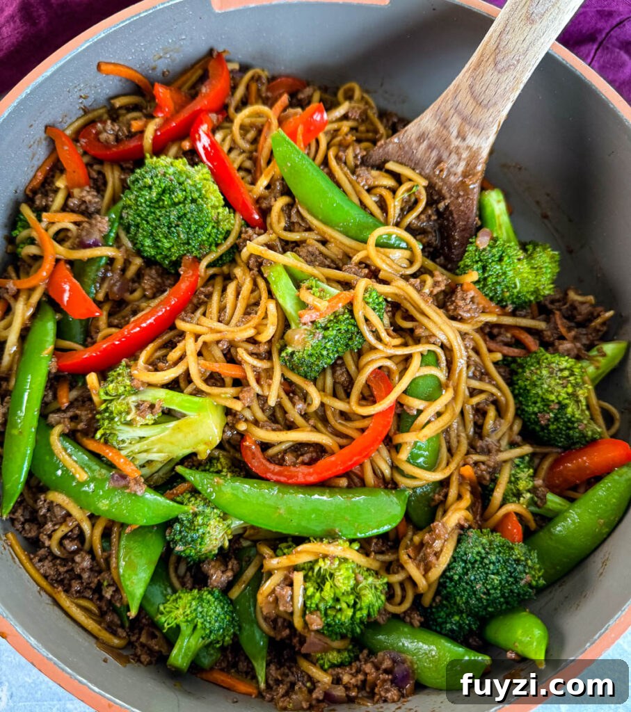 ground beef lo mein in a skillet with a wooden spoon