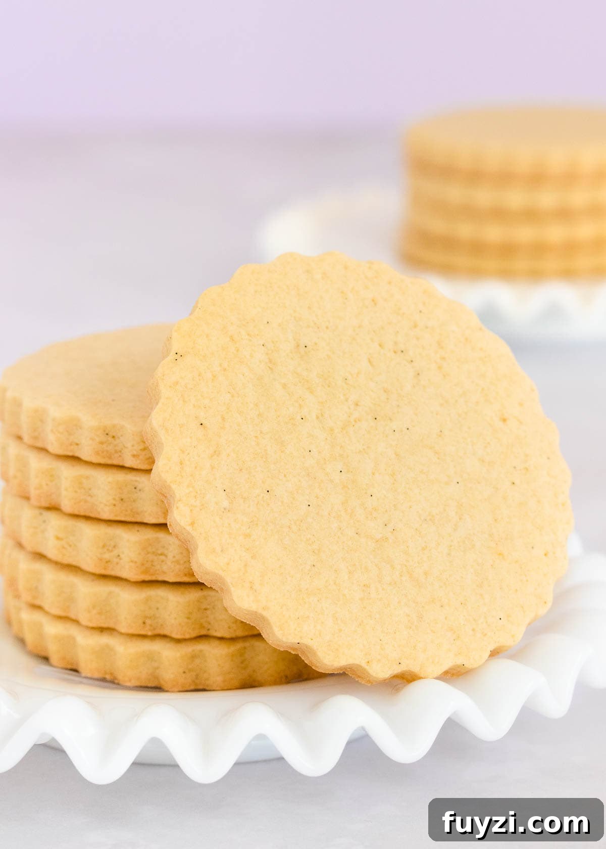 How to Make Soft Gluten-Free Sugar Cookies 2 A stack of gluten free sugar cookies on a white glass plate with a ruffled edge.