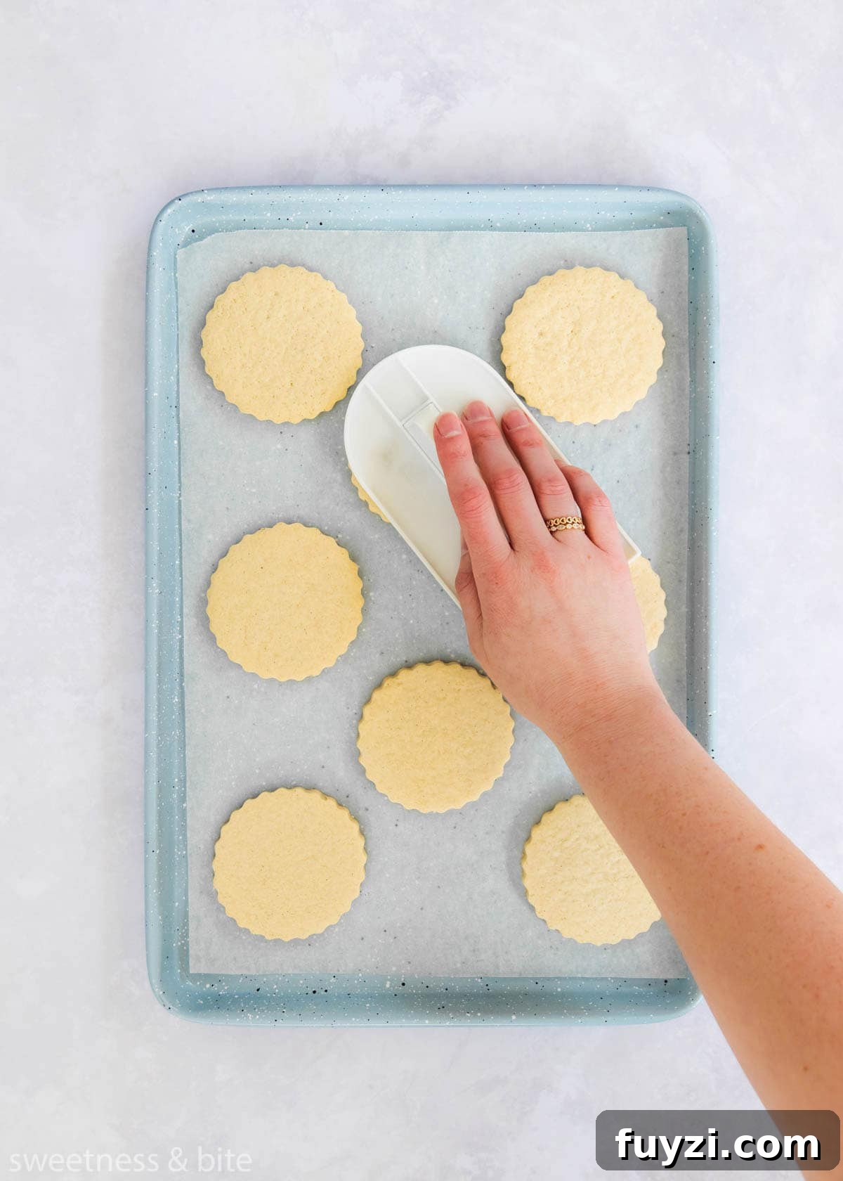 How to Make Soft Gluten-Free Sugar Cookies 4 A hand using a fondant smoother to flatten cookie tops.
