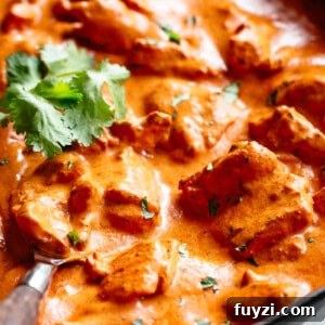 A close-up shot showcases a pan filled with a vibrant, creamy tomato-based curry.