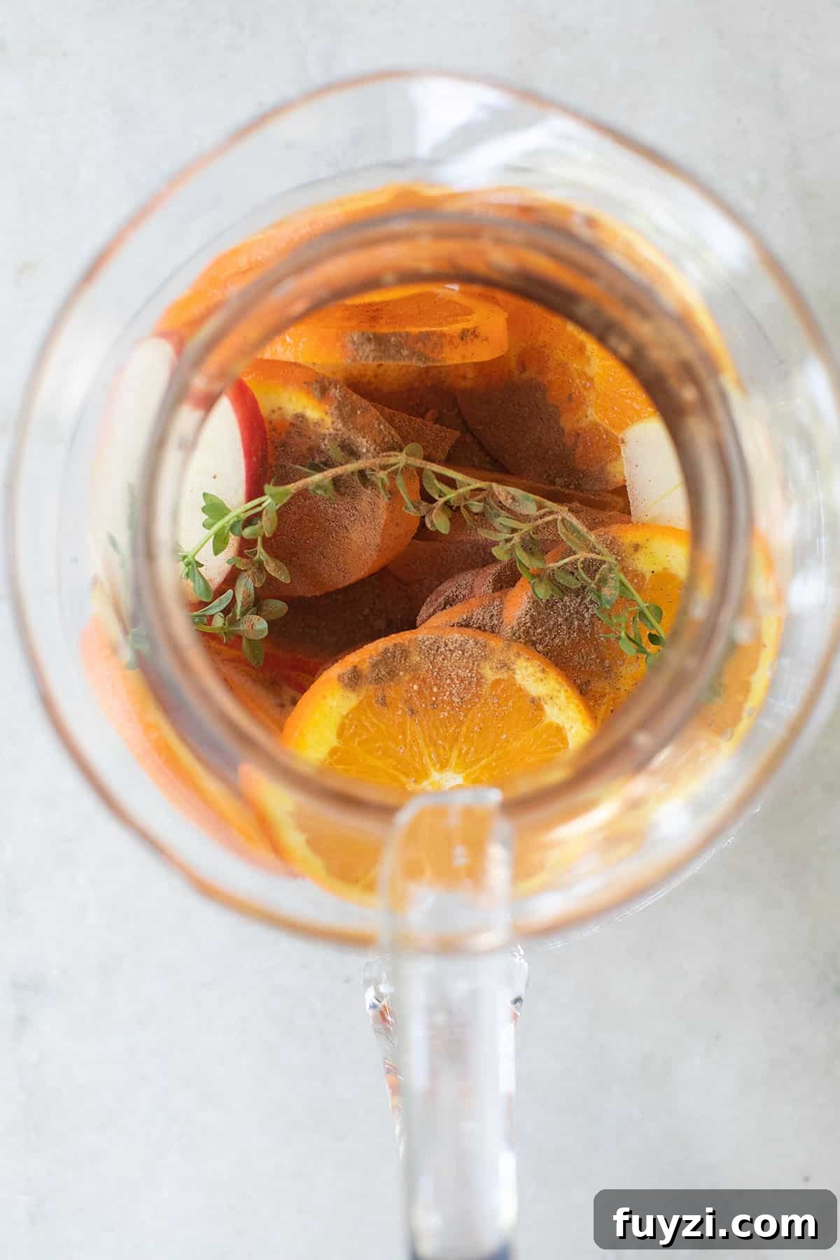 Spiced Autumn Apple and Pear Sangria Recipe 5 Sangria ingredients in a pitcher with thyme and cinnamon.