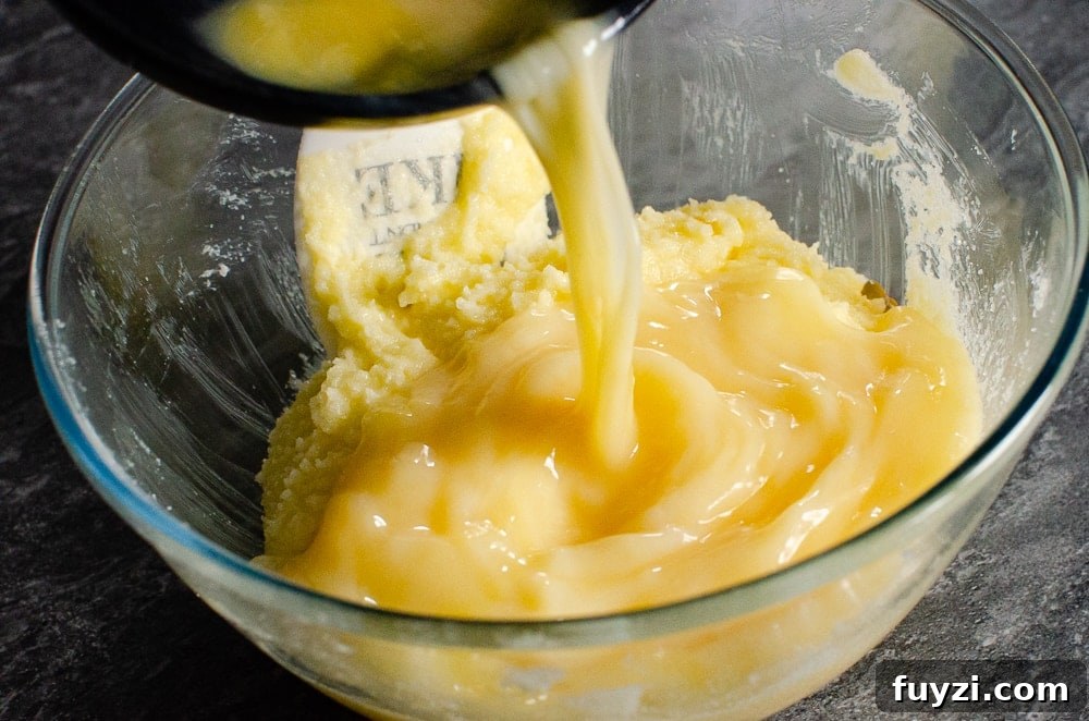 Fudgy Chunky Chocolate Chip Brownies Recipe 15 Eggs being poured into the butter mixture in a glass bowl
