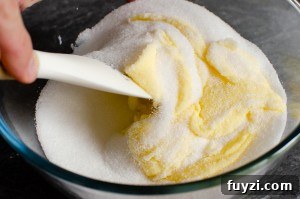 Fudgy Chunky Chocolate Chip Brownies Recipe 4 Mixing butter and sugar in a glass bowl with a white spatula