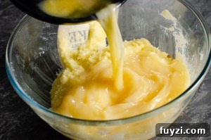 Fudgy Chunky Chocolate Chip Brownies Recipe 5 Eggs being poured into the butter mixture in a glass bowl