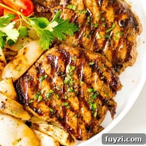 juicy grilled pork chops with a savory marinade next to onions and tomatoes