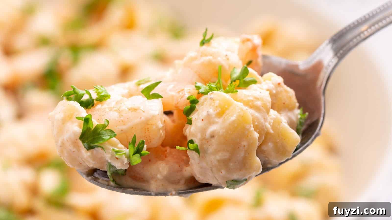 27 Crowd-Pleasing Outdoor Potluck Recipes for Late Summer 28 Close-up of a spoon holding seafood pasta salad garnished with parsley, with more salad in the background.