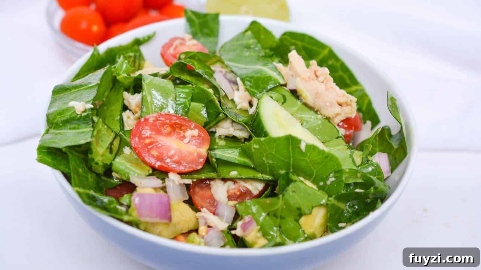 27 Crowd-Pleasing Outdoor Potluck Recipes for Late Summer 10 A bowl of fresh salad with leafy greens, cherry tomatoes, cucumber slices, red onion, and chunks of tuna. A lime wedge and cherry tomatoes are in the background.