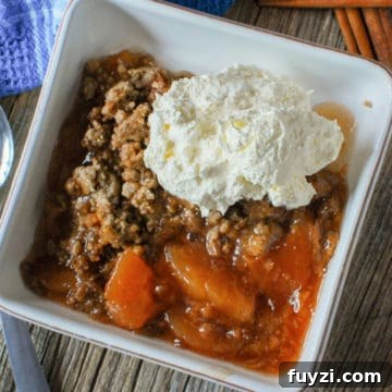 3-Ingredient Crock Pot Apple Spice Dump Cake (Video) 4 Apple spice dump cake in a white bowl with whipped cream