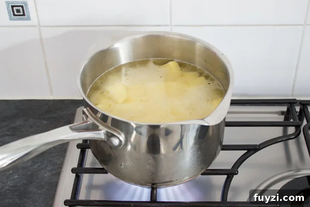 Potatoes coming to a boil in a large saucepan.