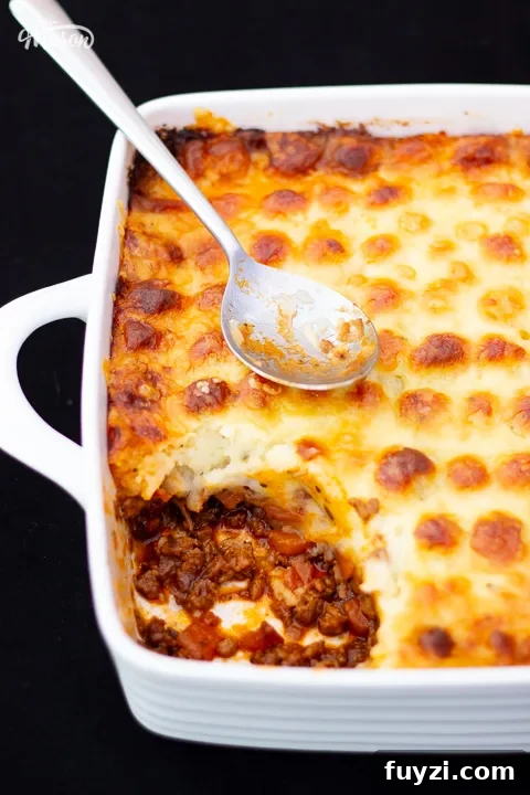 Baked Shepherd's pie in a white dish with a spoon.