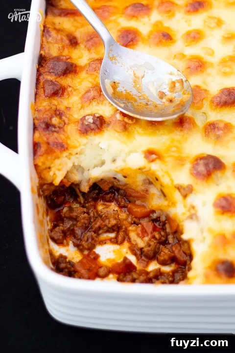 Cooked shepherd's pie in a white dish with a portion spooned out.