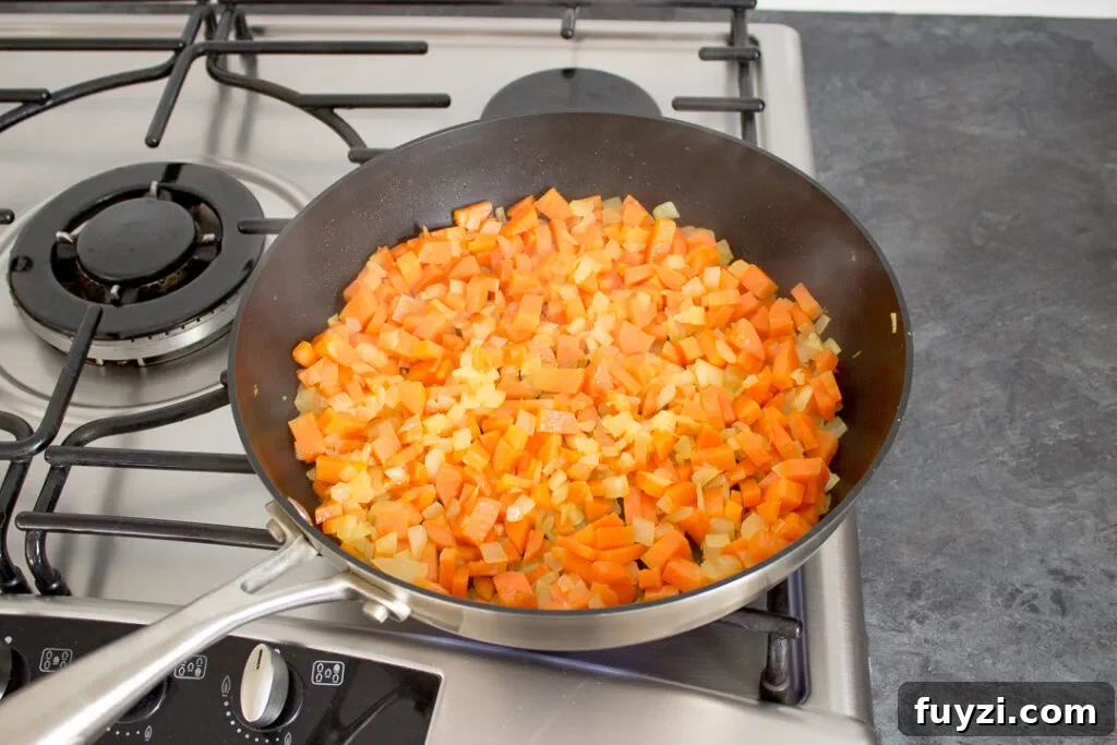 Root vegetables softening in a frying pan.