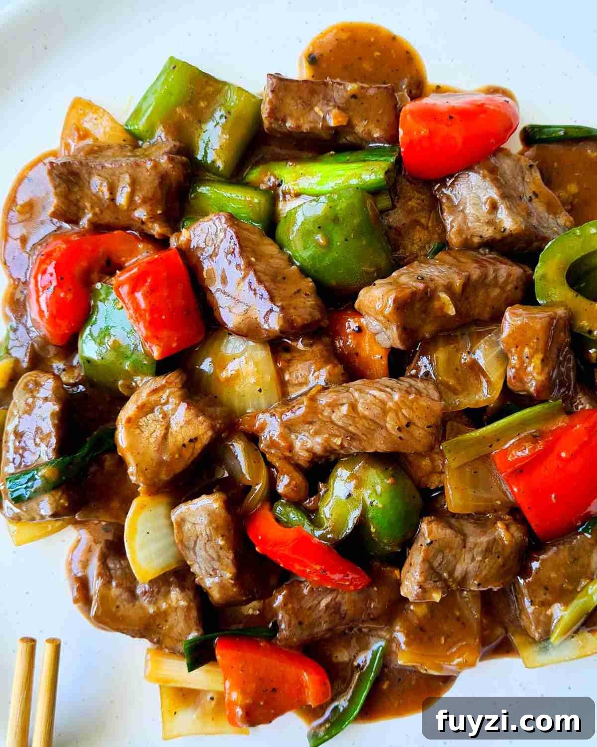 Restaurant-Style Black Pepper Beef Stir-Fry 10 Glossy beef cubes and vegetables on a white plate