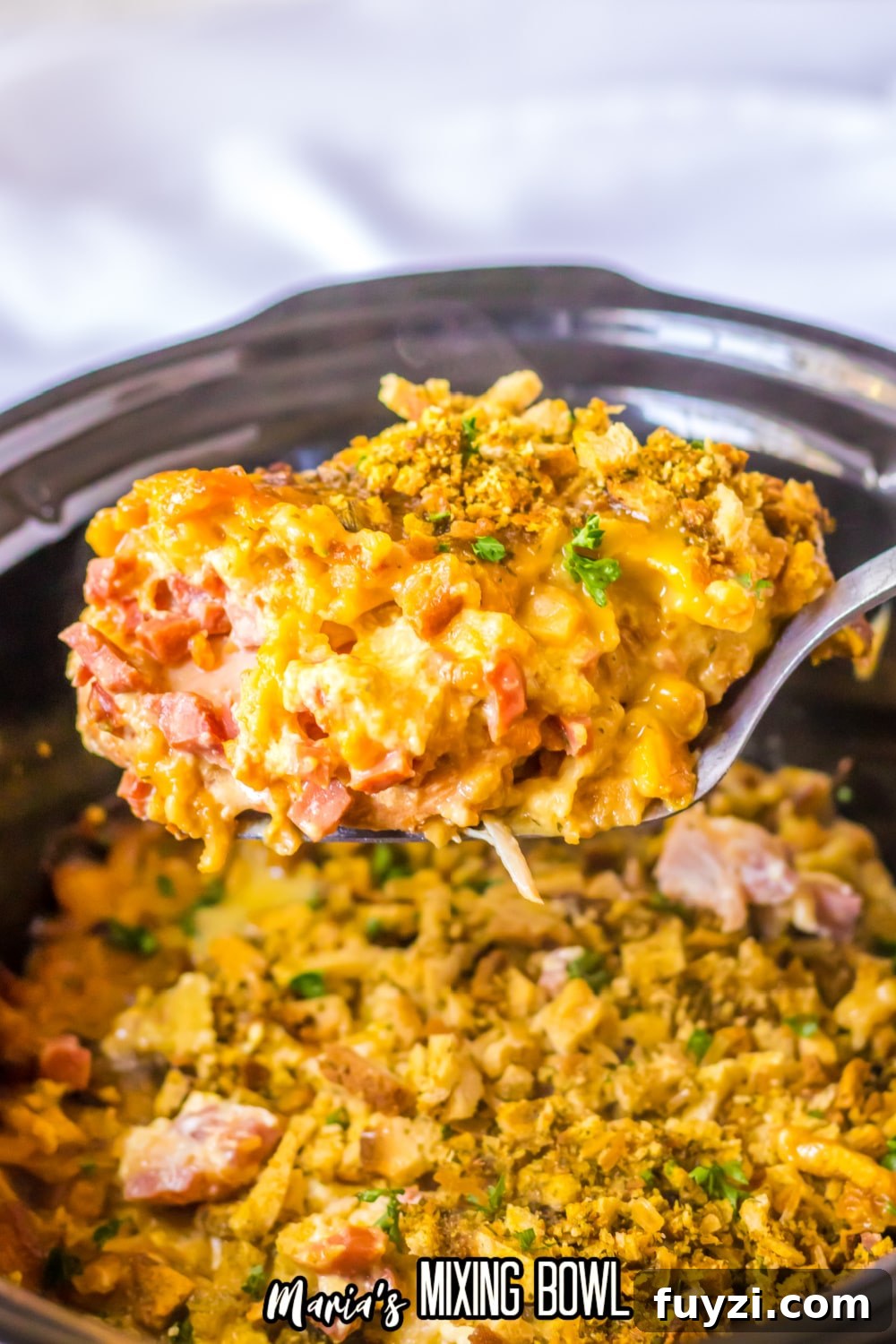 Slow Cooker Chicken Cordon Bleu Recipe with Ham and Swiss 3 spoonful of chicken cordon bleu held in the air above a slow cooker