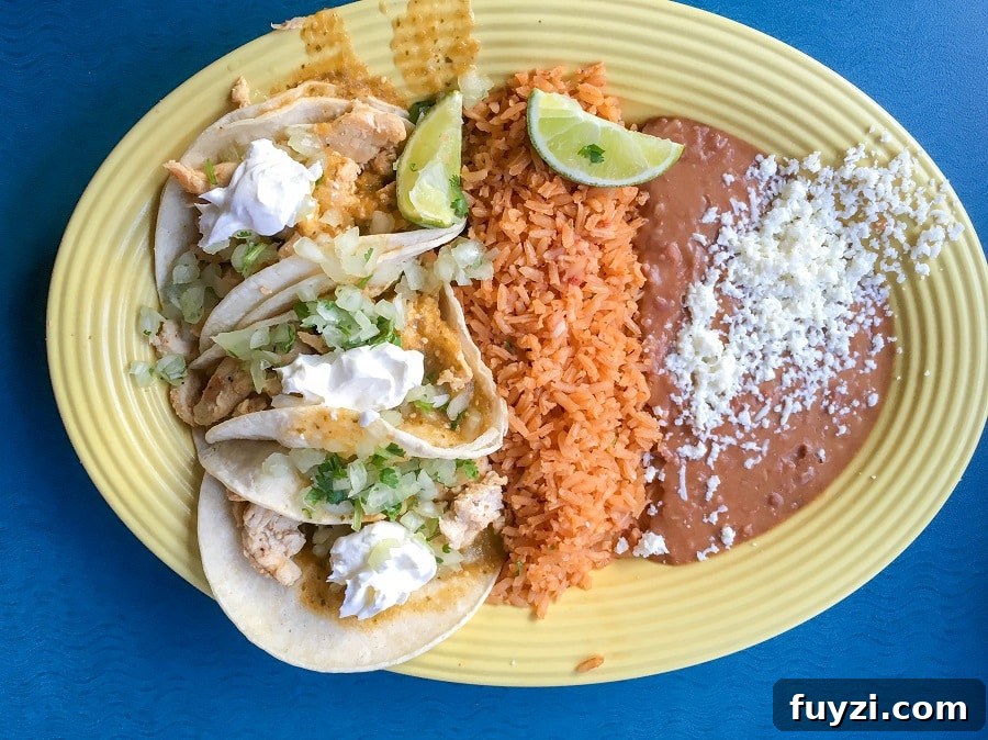 a yellow plate with three gluten-free tacos, Mexican rice, and refried beans at Rancho del Zocalo in Disneyland