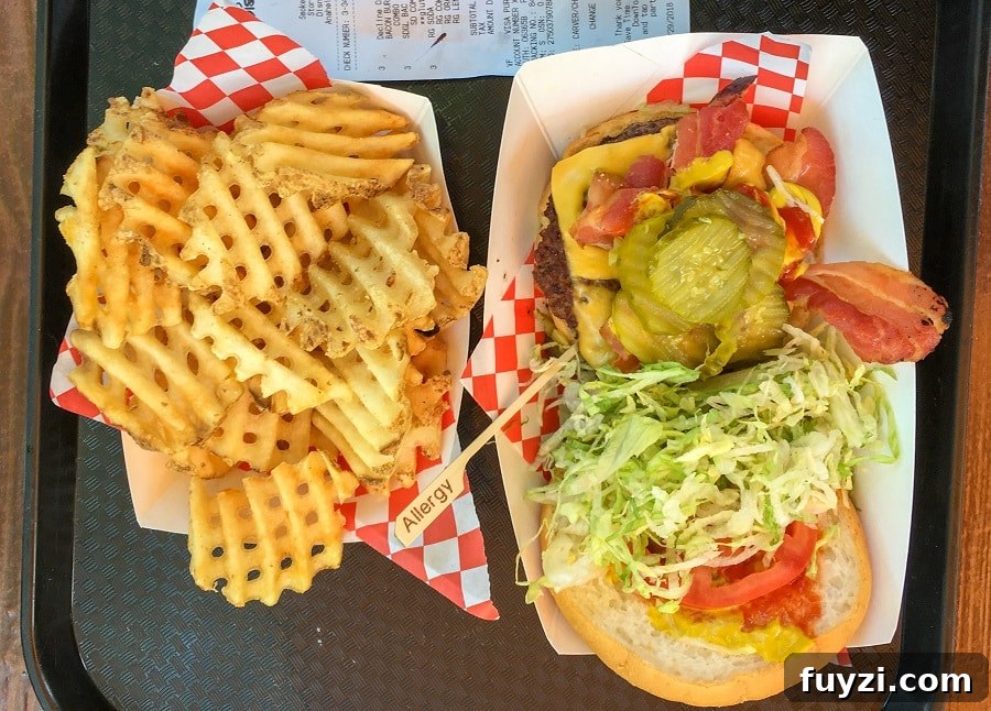 an open bacon cheeseburger with toppings and a tray of gluten-free waffle fries at Smokejumpers Grill in Disney California Adventure