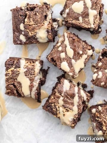 tahini brownies on a white background drizzled with tahini sauce