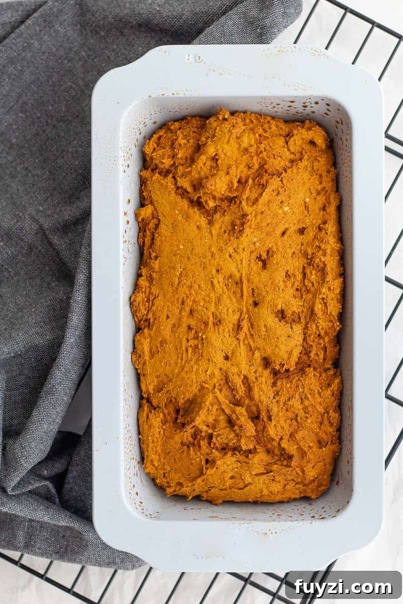 pumpkin bread in a loaf pan on a cooling rack