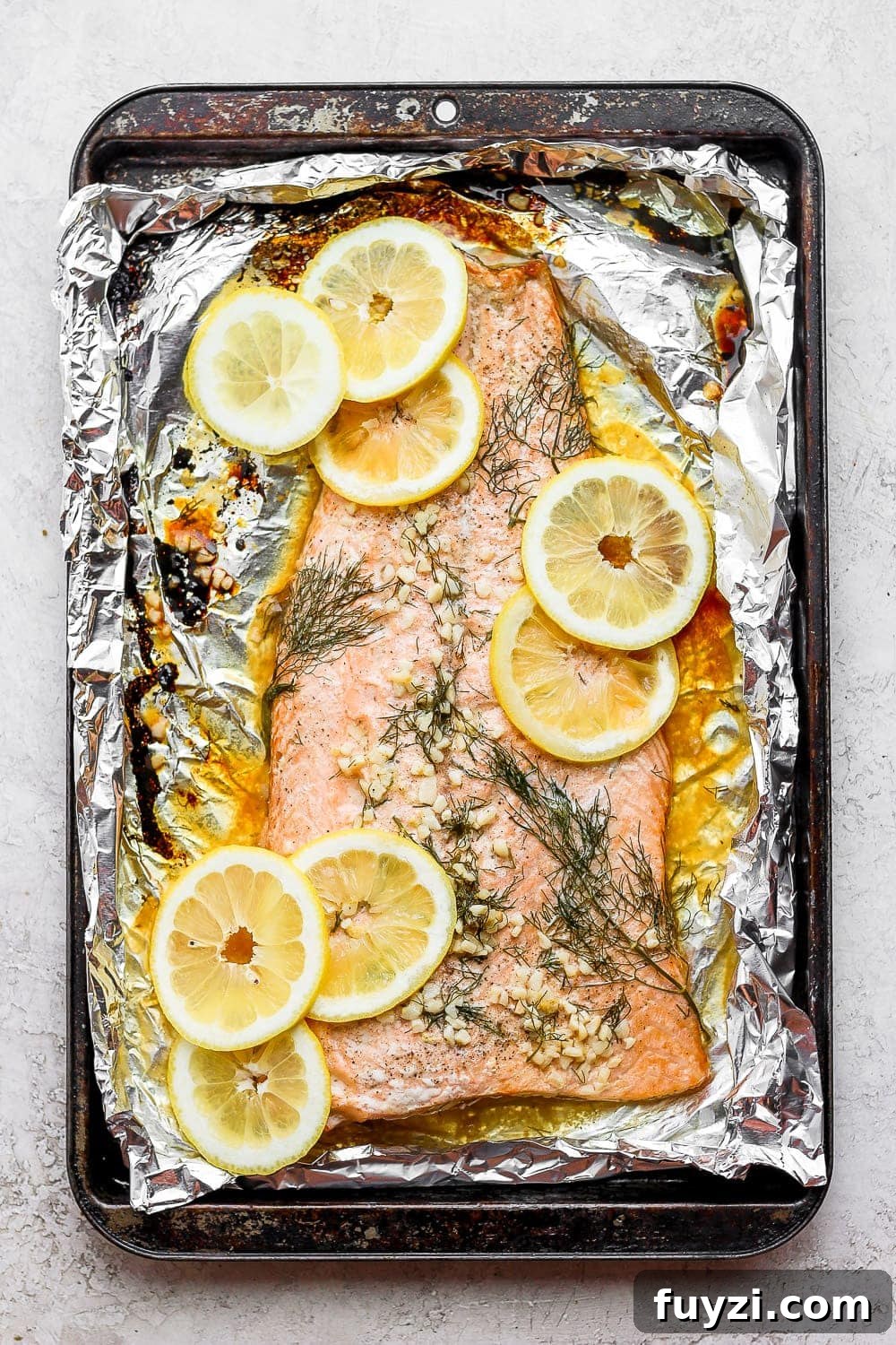 This perfectly cooked oven baked salmon in foil will give your family a delicious, healthy meal! It's naturally gluten-free and high-protein. large salmon fillet on tin foil with lemons