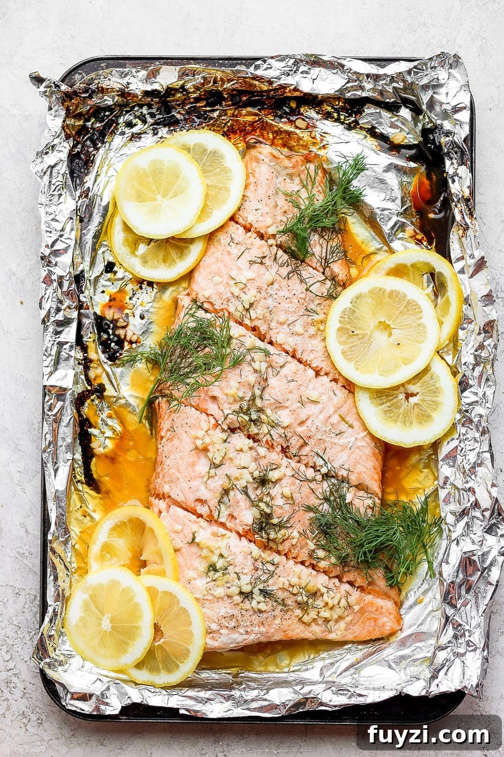 This baked salmon recipe is first marinated in a delicious lemon garlic sauce, then wrapped in tin foil and baked to a flakey perfection! large salmon fillet cut into single servings