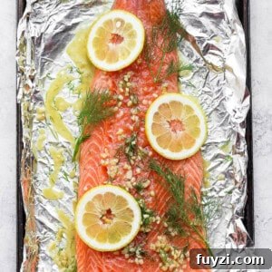 Oven-Baked Salmon in Foil: Flaky, Tender Fillets 4 salmon on top of foil with dill and lemons.