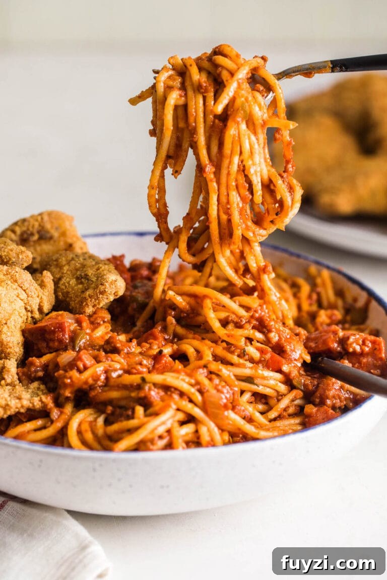 Forkful of Soul Food Spaghetti over bowl with fried fish.