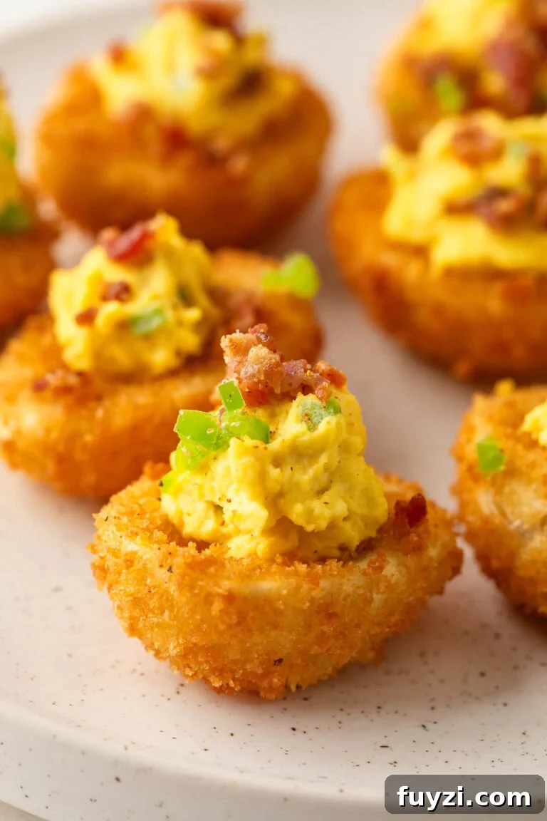 Plate of Fried Deviled Eggs topped with Jalapeño and Bacon.